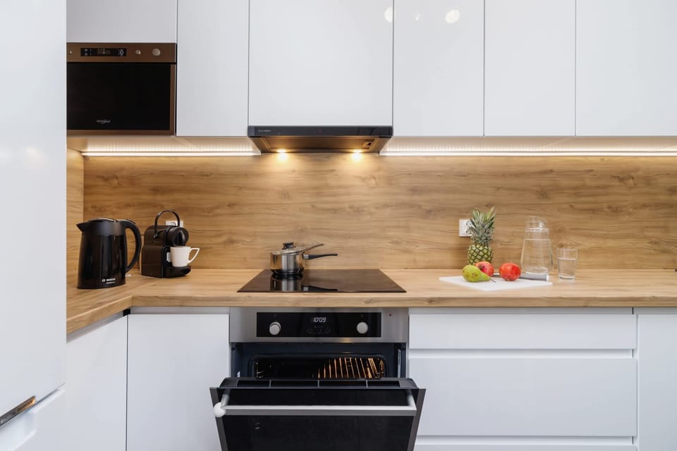 A modern kitchen with white cabinets, wooden countertops, and high-quality appliances.
