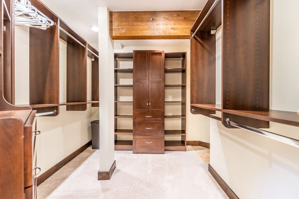 Your spacious walk-in closet offers abundant storage with rich wood shelving and hanging space for all your belongings.