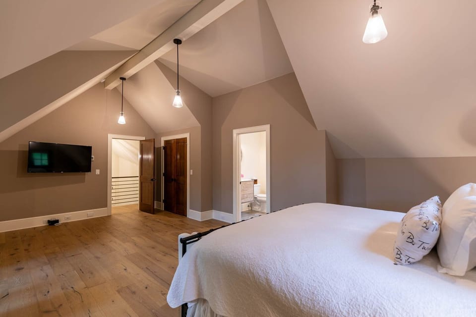 Soaring vaulted ceilings and warm hardwood floors give this upper-level bedroom an airy, retreat feel with a private bath steps away.