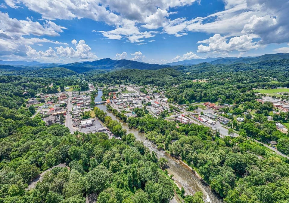 Elevated view overlooking Bryson City with rolling mountain ridges and a river corridor visible below. The central location provides convenient access to downtown and Smoky Mountain attractions.