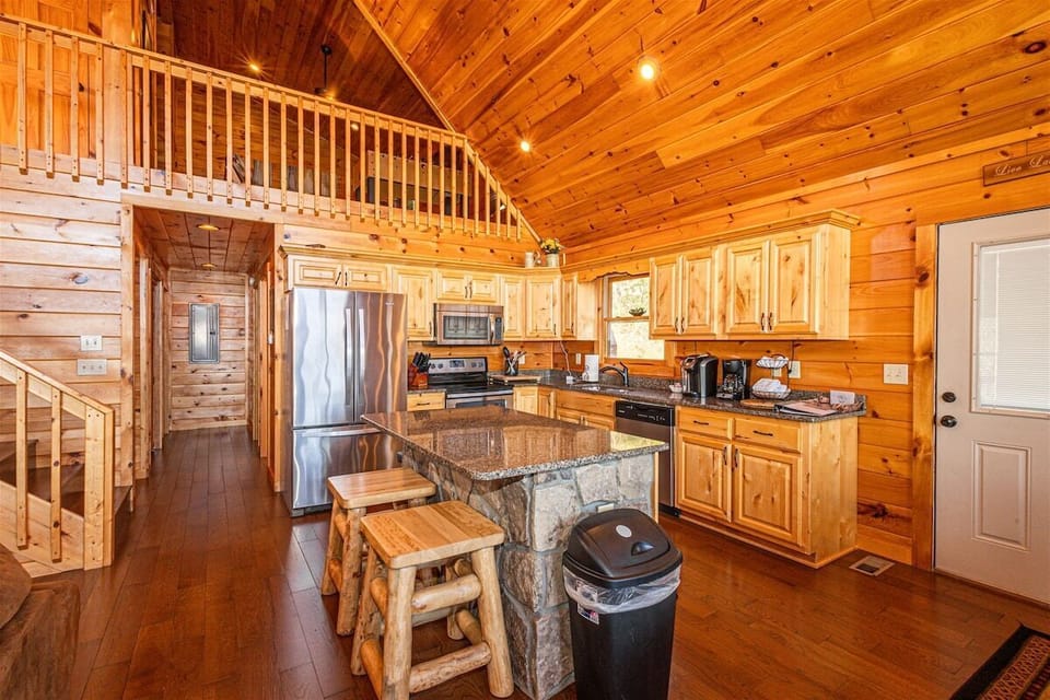 The fully equipped kitchen includes granite countertops, stainless steel appliances, wood cabinetry, and open views into the living room. This spacious layout supports group meals and entertaining.