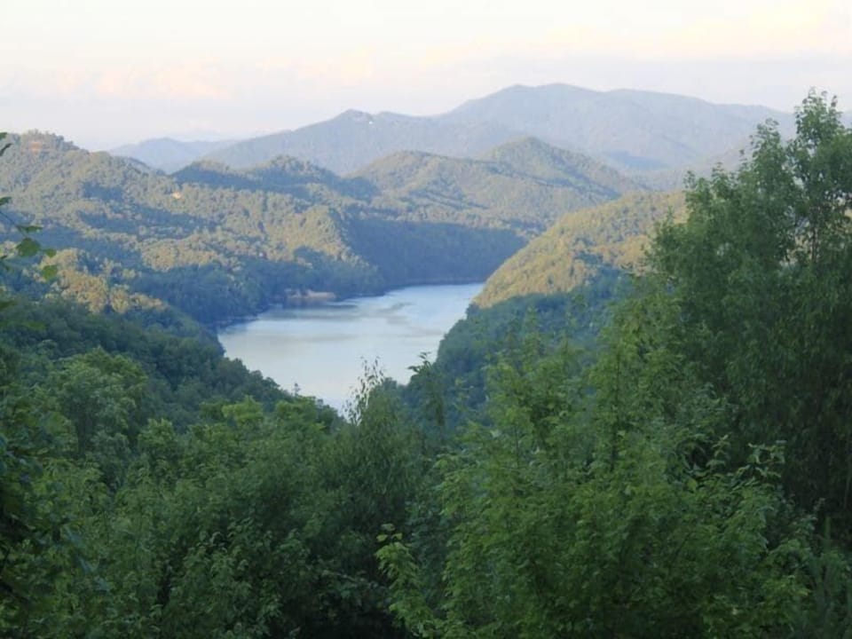 Elevated views overlook Lake Fontana surrounded by rolling Smoky Mountain ridges and dense forest. The scenic landscape is visible from the cabin property.