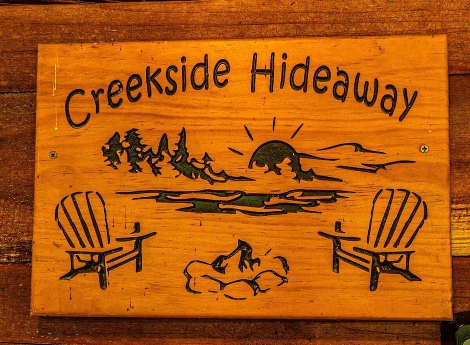 Wooden Creekside Hideaway welcome sign displayed at the cabin entrance. This property identification sign highlights the creekside cabin rental in Bryson City, North Carolina.