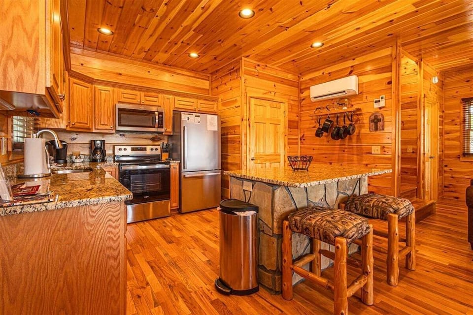 Well-appointed cabin kitchen with stainless steel appliances, breakfast bar seating, and knotty pine walls at this Bryson City vacation rental near Harrah's Cherokee Casino and the Great Smoky Mountain Train.