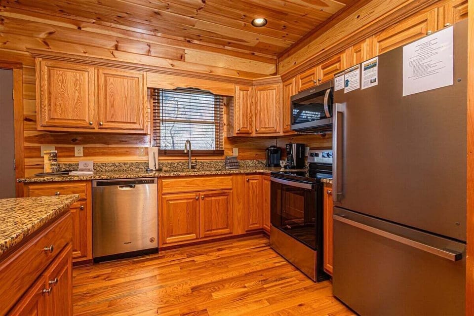 Spacious full kitchen featuring granite countertops, custom wood cabinetry, and modern appliances inside this Smoky Mountains cabin rental in Bryson City.