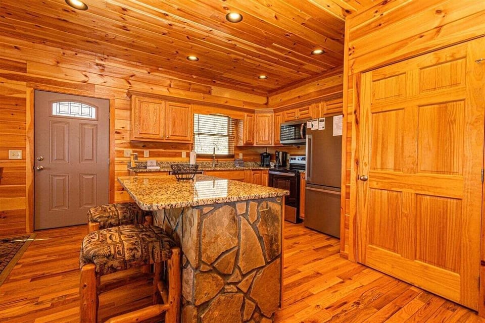 Open-concept kitchen and dining area at A Treehouse View over Lake Fontana with granite countertops, wood cabinetry, and rustic finishes in Bryson City near the Smoky Mountains attractions and NOC.