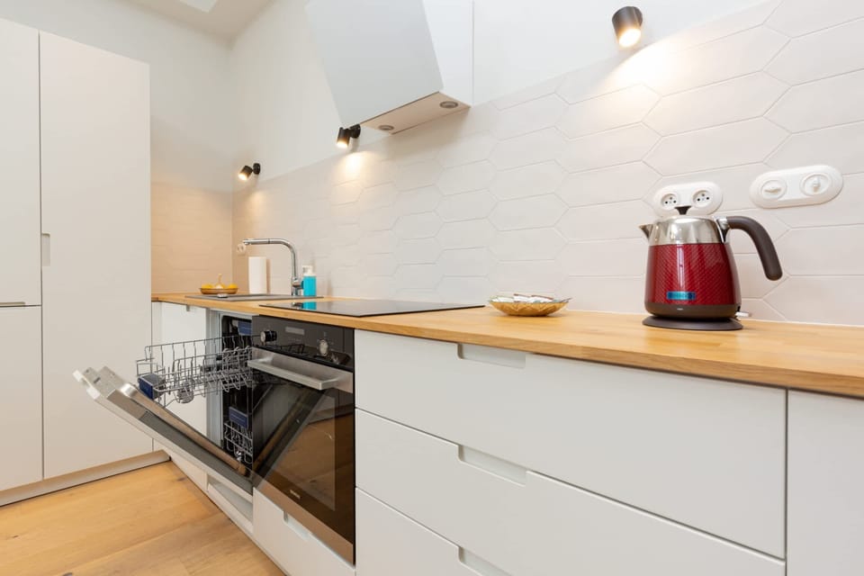 A modern kitchen with white cabinetry, wooden countertops, and essential appliances for convenient cooking.
