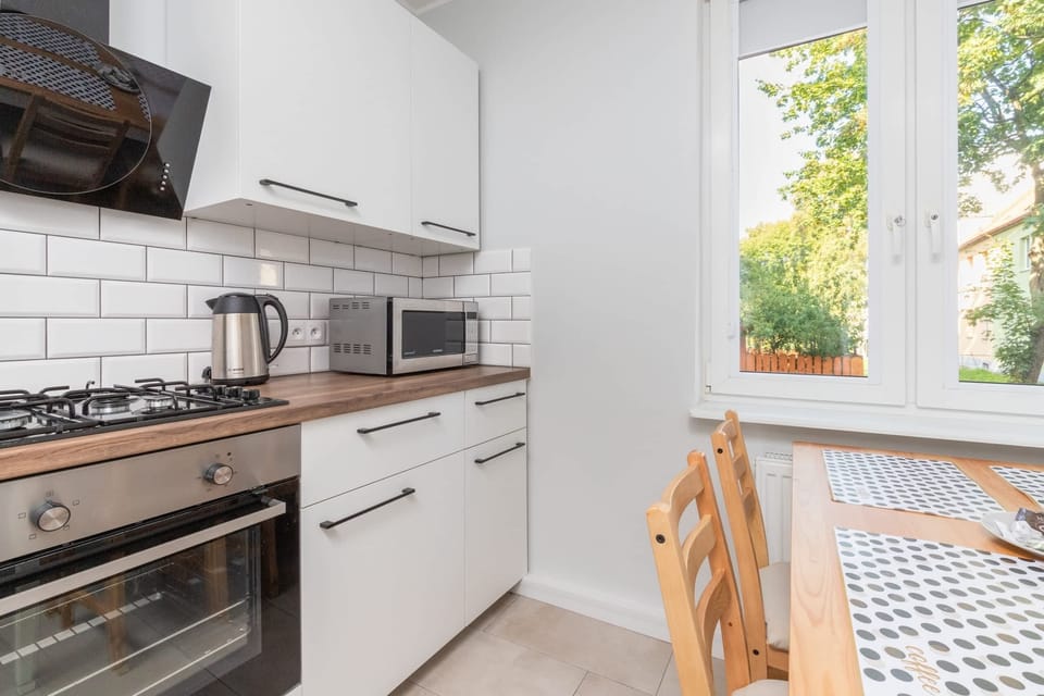 A fully equipped kitchen with white cabinets, a large stove, and a window letting in daylight.
