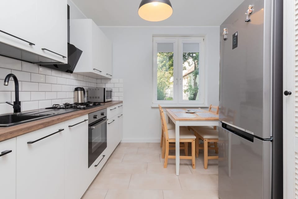 A fully equipped kitchen with white cabinets, a large stove, and a window letting in daylight.
