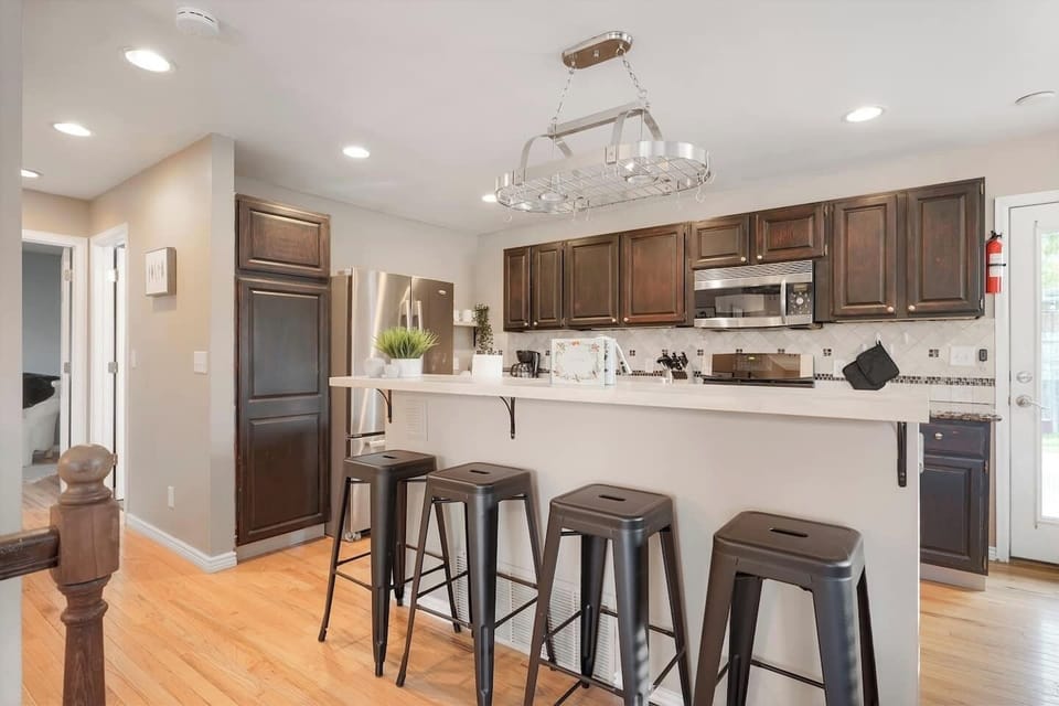 - Dark wood cabinetry and sleek stainless steel appliances bring modern warmth
- Enjoy quick bites or morning coffee at the long bar with seating for four
- Open design allows guests to cook, snack, and chat without missing a moment