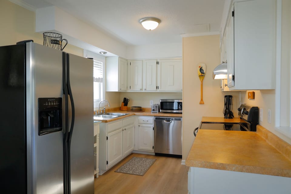 Galley style kitchen stocked with dishes, silverware and cooking utensils.