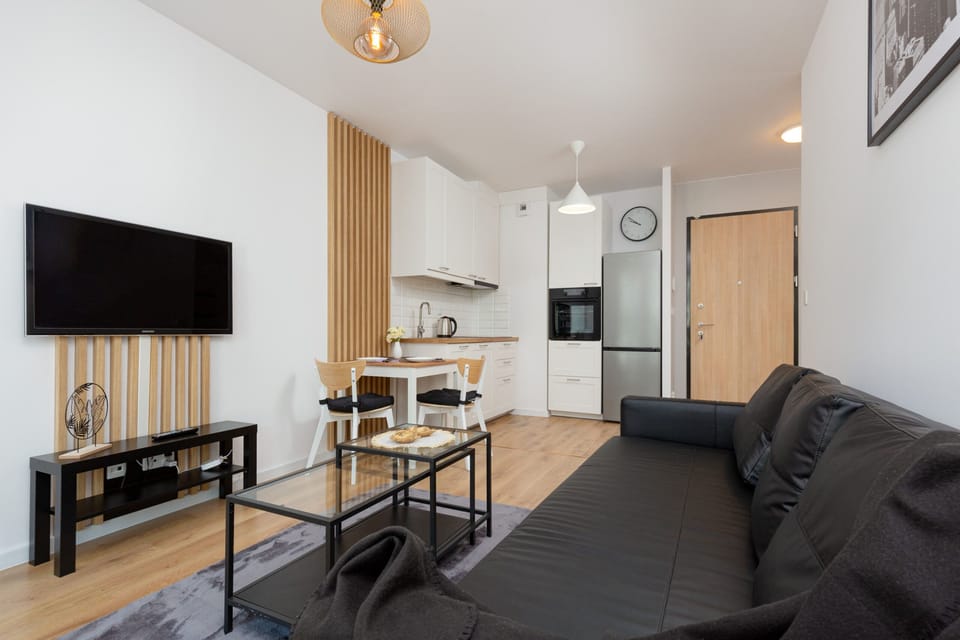 Another view of the living room, showcasing a wall-mounted TV, a sofa, and decorative wooden wall panels.