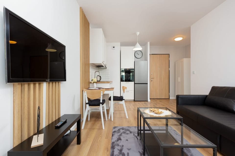 A bright and spacious living room with a sofa, coffee table, and a view of the modern, open kitchen.