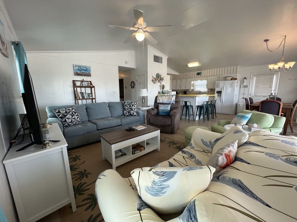 Relax in your spacious living area with coastal-themed furnishings and open kitchen, perfect for unwinding after beach days.