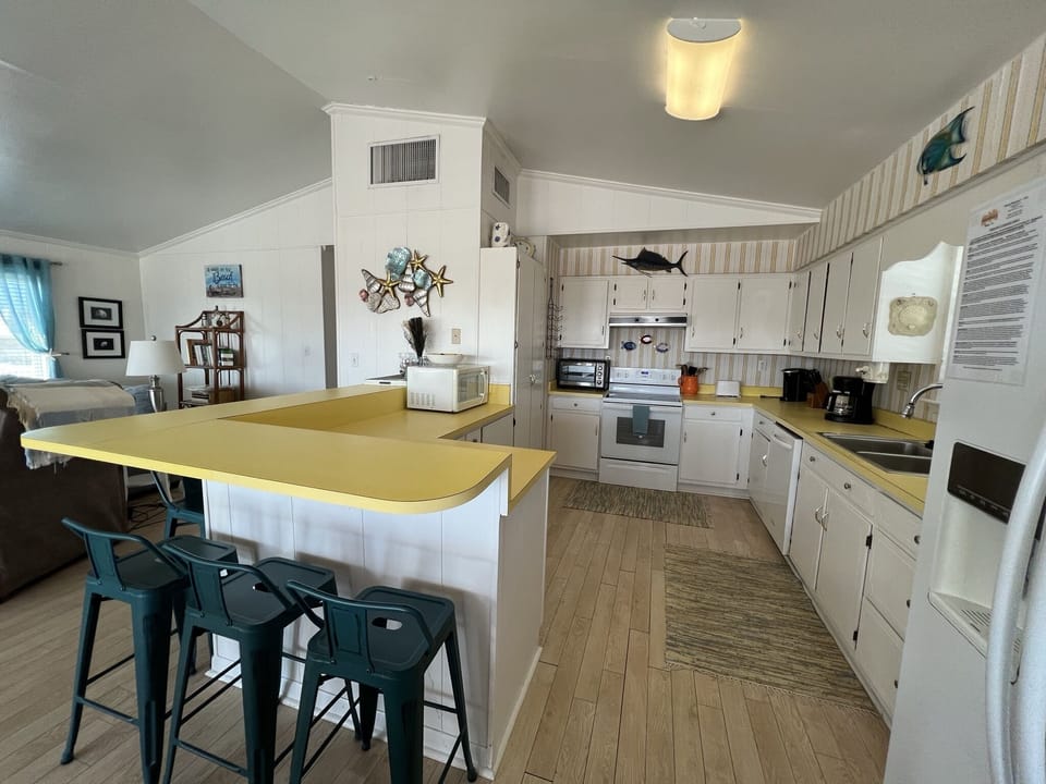 Your spacious kitchen invites culinary adventures with its bright island, full appliances, and charming coastal touches throughout.