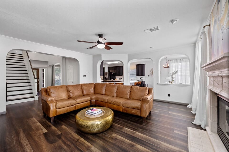 Additional view of the open living room with leather sectional and staircase leading upstairs.