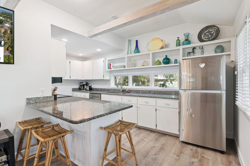 Your bright, cheerful kitchen invites you to whip up vacation meals or morning coffee at the center island, complete with cozy bamboo stools and charming curated décor.
