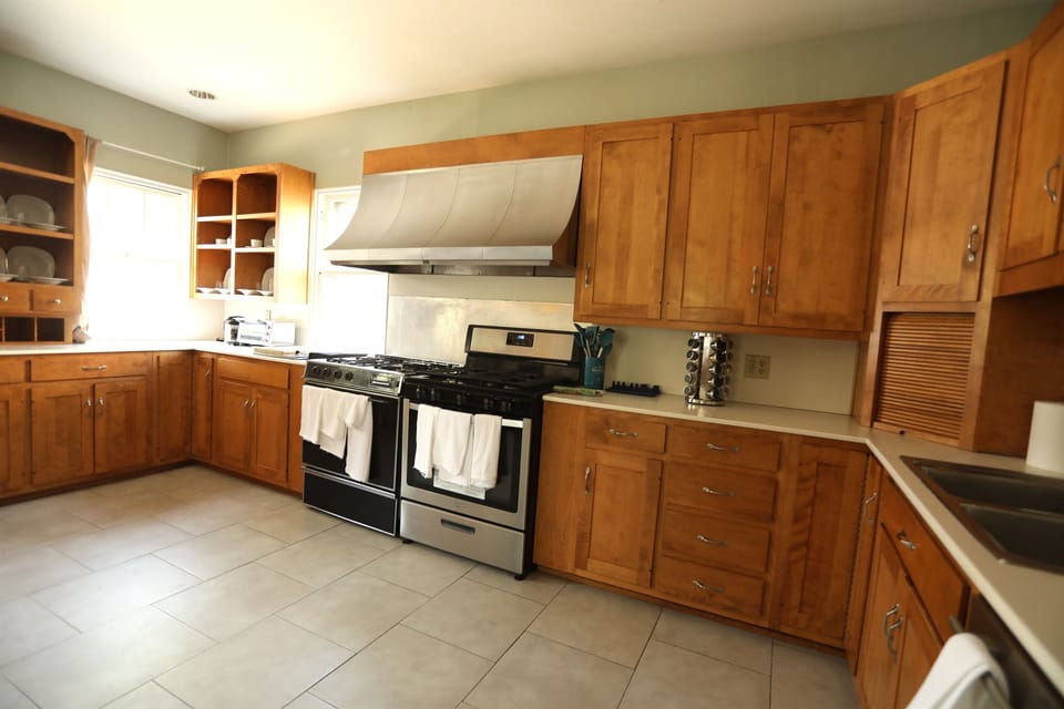 Kitchen features three cooking surfaces (two stove ovens and a JennAire cooking countertop), a toaster oven to the left of the JennAire, and a Keurig coffee maker hidden in the retractable storage to the right.