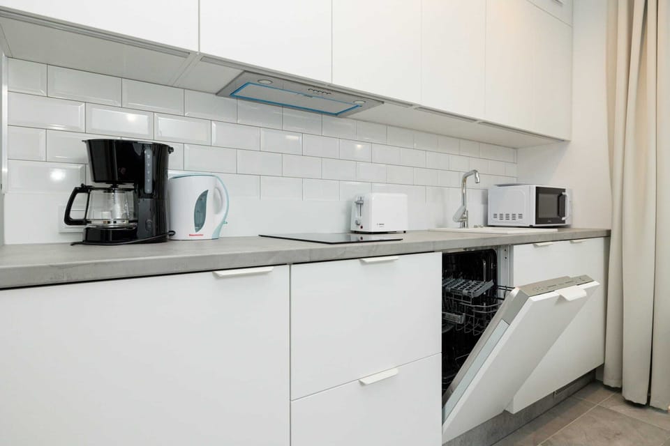 A sleek kitchen with white cabinetry and modern appliances, blending seamlessly with the dining area in an open floor plan.