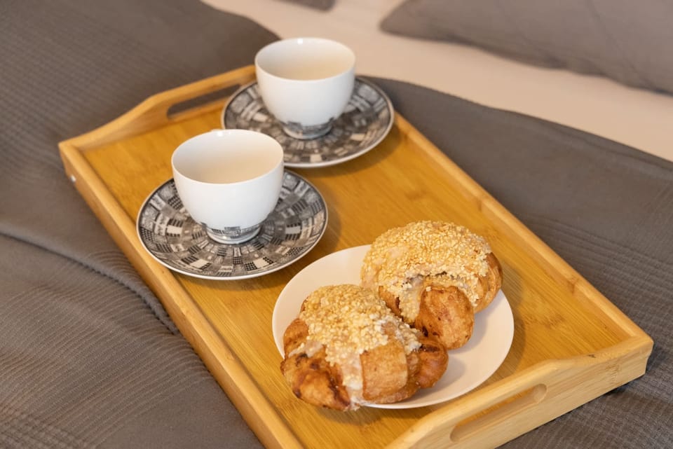 Close-up of a wooden tray with a cup of coffee and pastries, offering a cozy breakfast setup.
