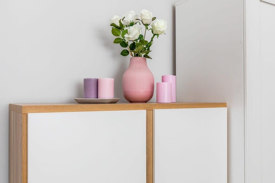 A white cabinet on which stands a decorative vase of flowers.