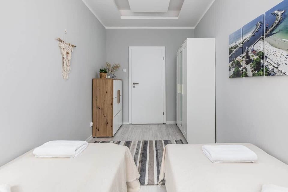 Another perspective of a room with two single beds showing a large white wardrobe and a chest of drawers to hold all personal items.