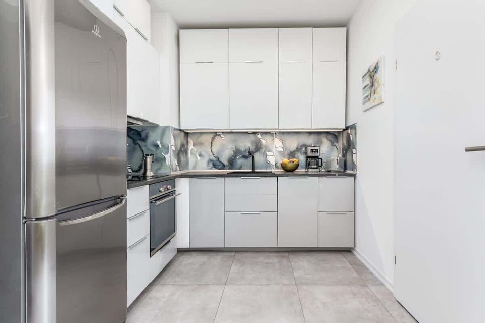 A functional kitchenette with white furniture and grey tiles on the floor provides a comfortable place to prepare home-cooked meals. The overall décor matches the entire interior.