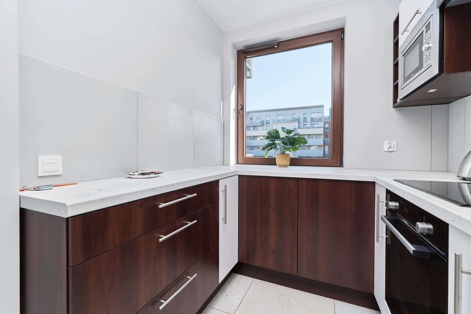 A modern kitchen with a combination of white and dark brown cabinets, stainless steel appliances, and a sleek countertop.