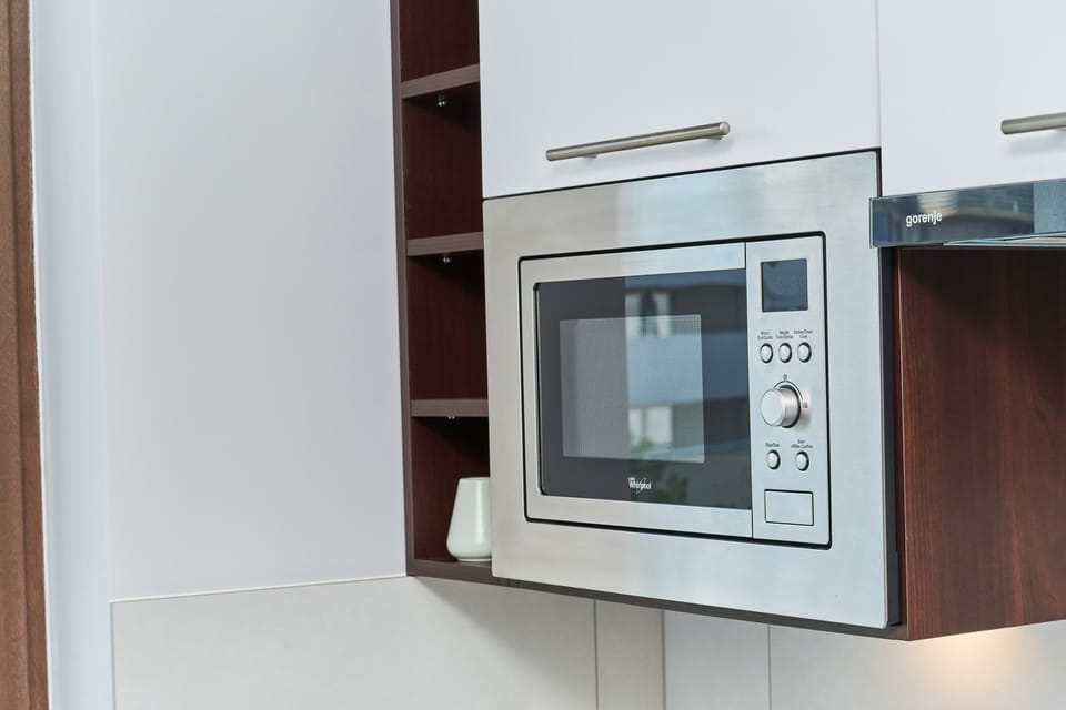 A close-up of the microwave built into the kitchen cabinets, showing its streamlined and functional design.