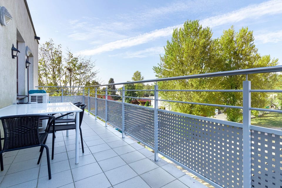 A spacious balcony with outdoor seating, surrounded by lush greenery and cityscape views.