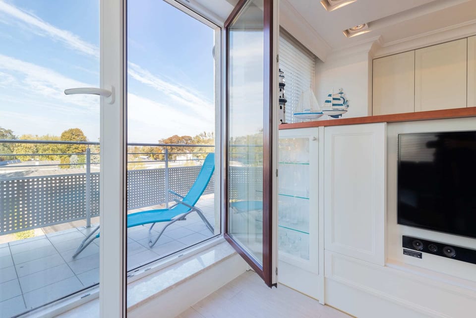 Exit to a spacious balcony with sun loungers and chairs.
