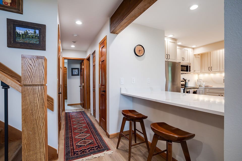 Step into your open-plan living space where rustic wood beams meet modern comfort. Perch at the breakfast bar for morning coffee.