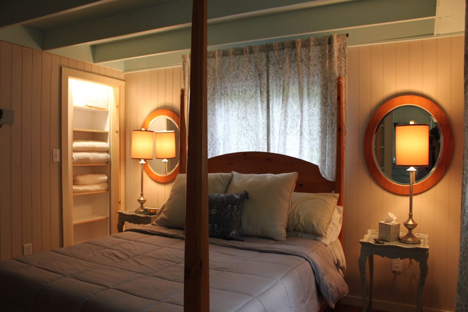 The primary queen bed, separated from the living space by an opaque french door.