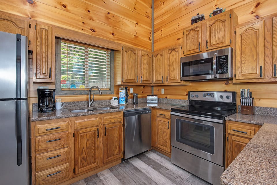 Your fully equipped kitchen features stainless steel appliances, granite countertops, and warm wood cabinetry—perfect for preparing family meals or morning coffee with natural light streaming in.