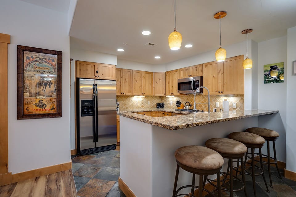 Cook up your favorite meals in this fully-equipped kitchen featuring granite counters, modern appliances, and cozy breakfast bar seating.