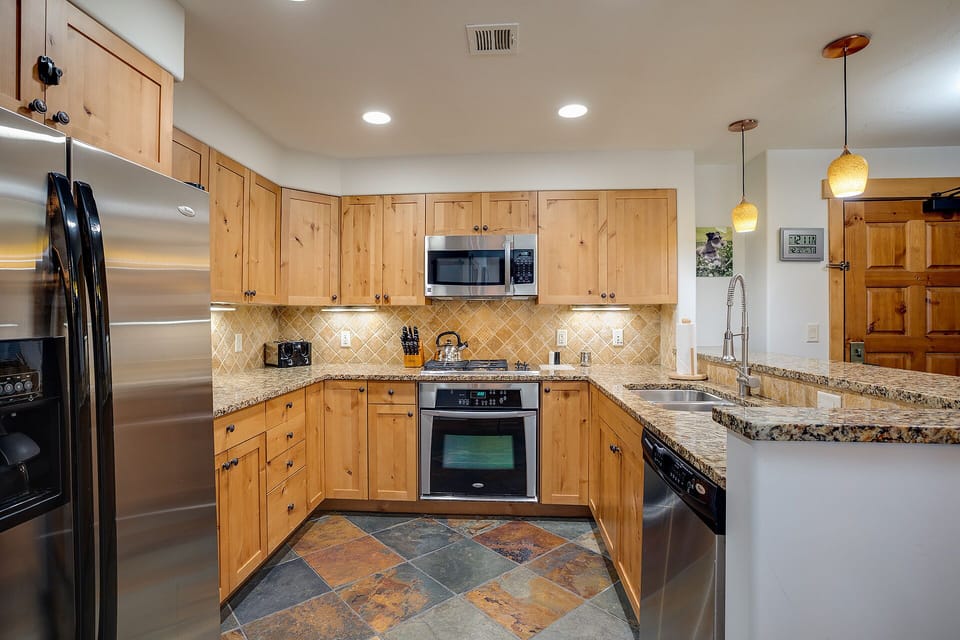 Cook your favorite meals in this spacious kitchen featuring granite countertops, stainless steel appliances, and warm wood cabinetry.