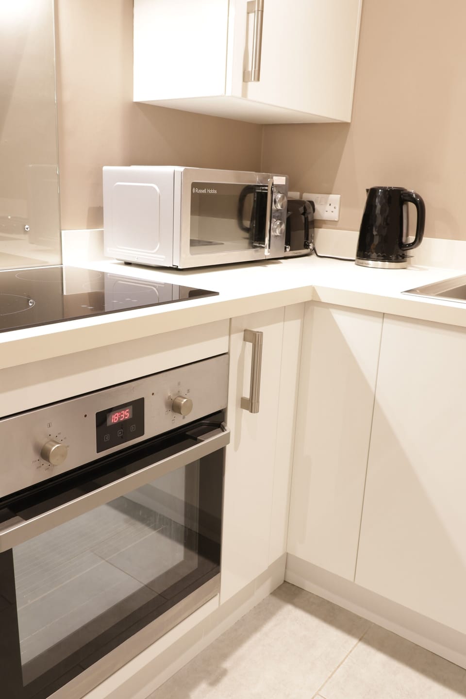 Modern fully equipped kitchen with oven, hob, microwave and kettle.
