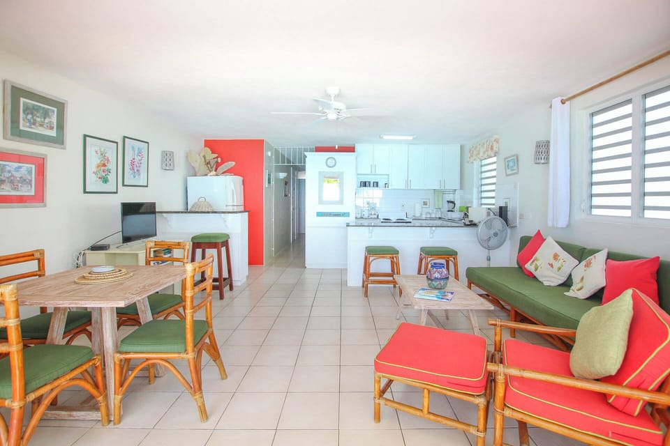 Tropical themed open plan living area with dining table, breakfast bar and kitchen