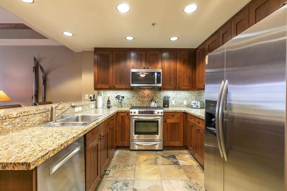 Open kitchen with stainless steel appliances and granite countertops