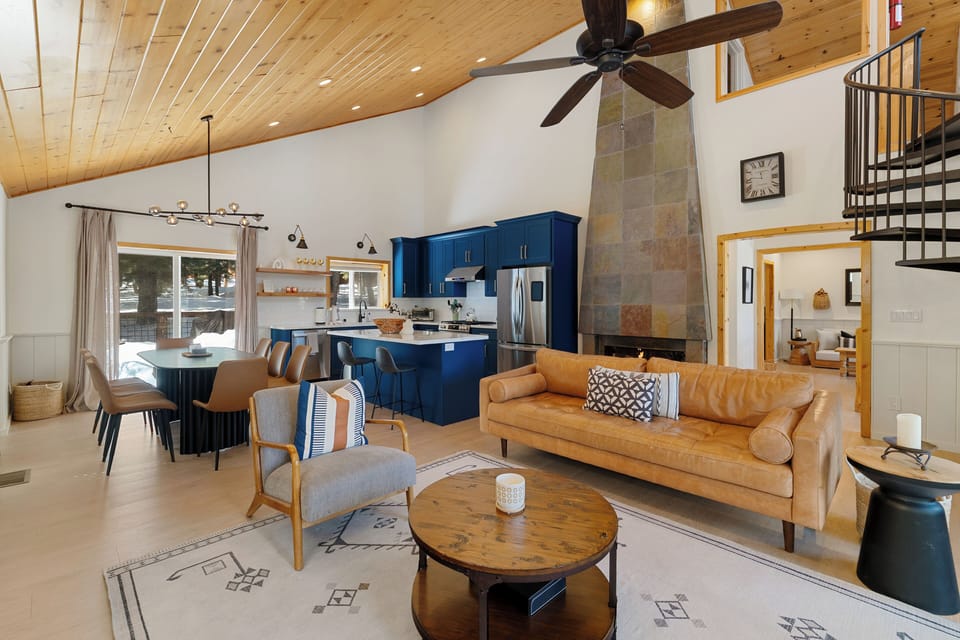 The sunny great room includes vaulted wood ceilings, a plush leather couch, and 