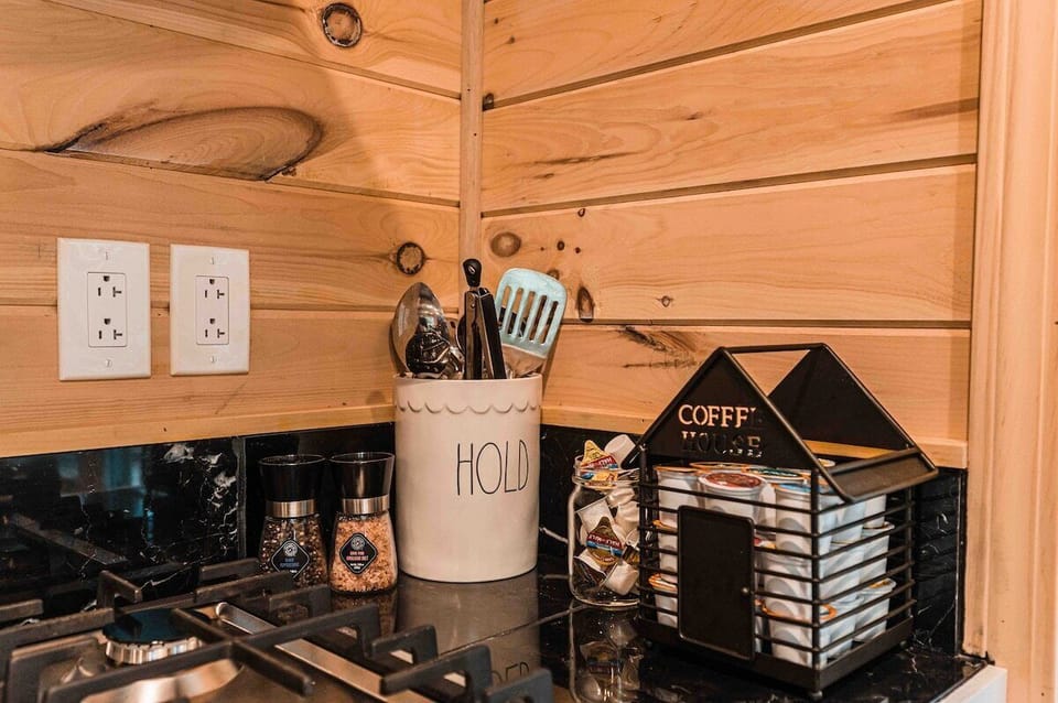 Kitchen essentials at MoonLight Treehouse: A cozy setup with a container labeled ‘HOLD’ for utensils, seasonings for flavor, and a charming ‘Coffee House’ organizer filled with K-cups to kickstart your day.