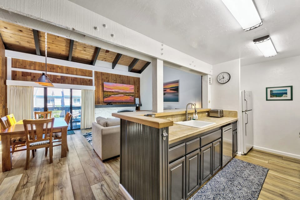 Your open-concept space seamlessly blends kitchen, dining, and living areas with exposed wood beams and warm touches for comfortable gatherings.