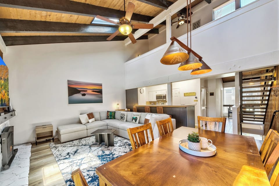 Relax in your stylish open-plan retreat with soaring beamed ceilings, cozy seating, and warm wood dining space perfect for gathering.