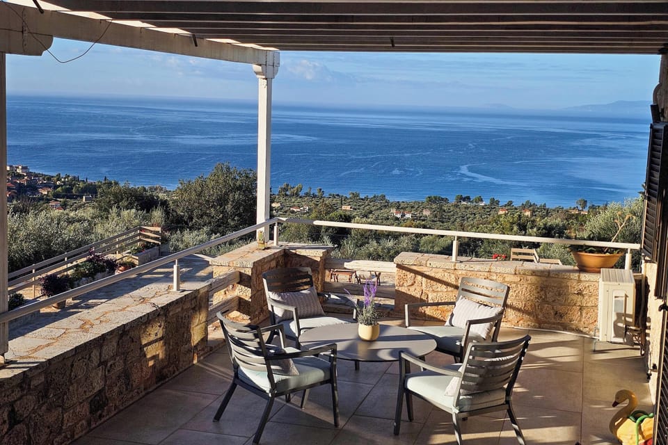 Second-floor balcony at the main villa with seating and wide views toward the sea and coastline.