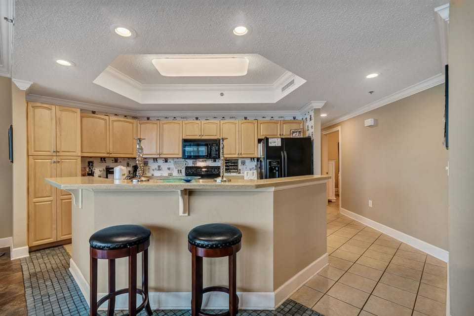 The large island with a breakfast bar provides a central hub for conversation and dining. Whether you're enjoying a quick bite or mingling during a get-together, this area combines comfort and function with style.
