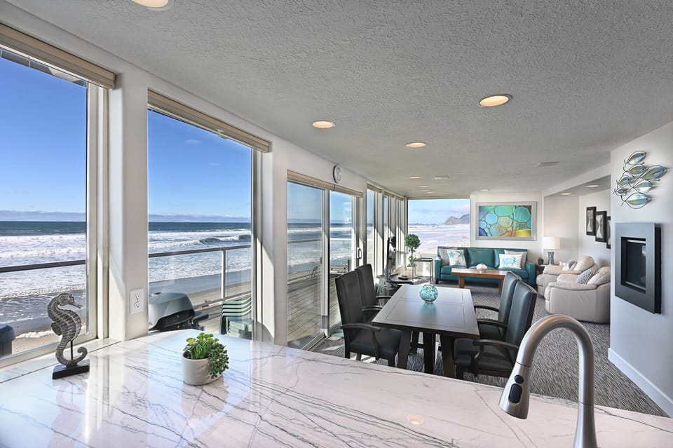 Airy dining space w/ floor-to-ceiling windows and coastal scenery all around.