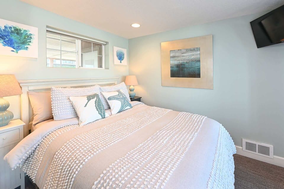 Serene bedroom w/ a neatly made bed and soft tones for restful nights.