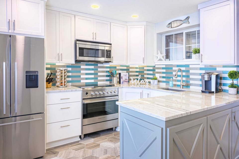 Modern kitchen w/ sleek finishes & ocean-inspired tile accents.