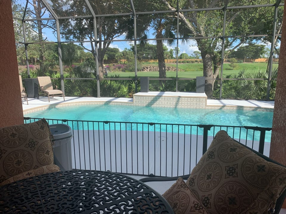 The back patio has a table and chairs overlooking the pool and golf course. 