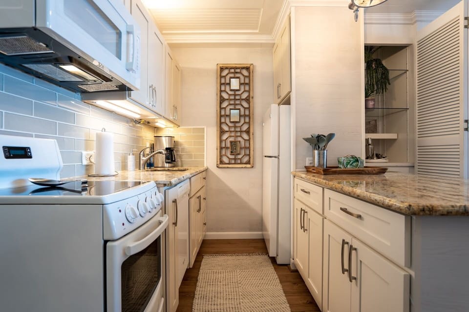 Your well-appointed galley kitchen features granite countertops, modern appliances, and coastal-inspired tile backsplash—everything you need to prepare meals in style during your stay.